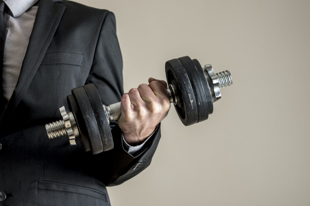 A businessman in business suit doing dumbbell biceps curl