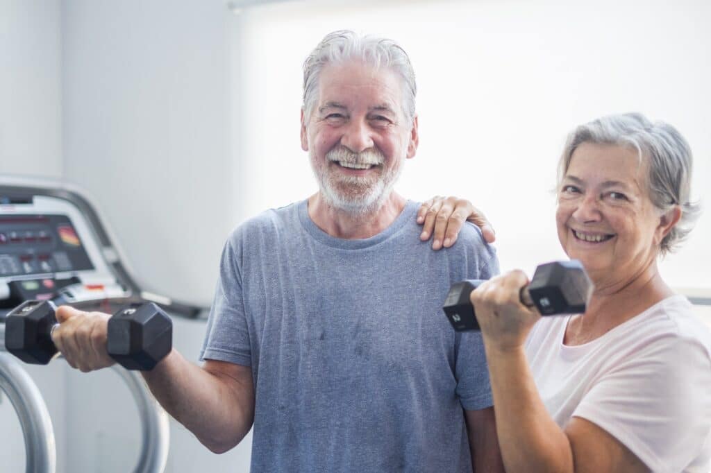 couple of two seniors at the gym holding a dumbbells